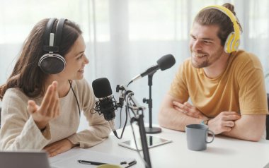 Young man and woman wearing headphones and doing a live podcast for their channel, communication and technology concept