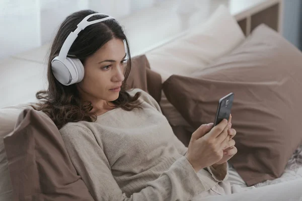Young Woman Relaxing Bed She Wearing Headphones Watching Videos Her — Stok fotoğraf
