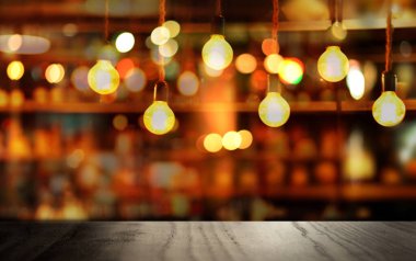 Karanlık gece arka planında küçük yuvarlak lamba ışığı olan siyah ahşap masanın tepesinde.