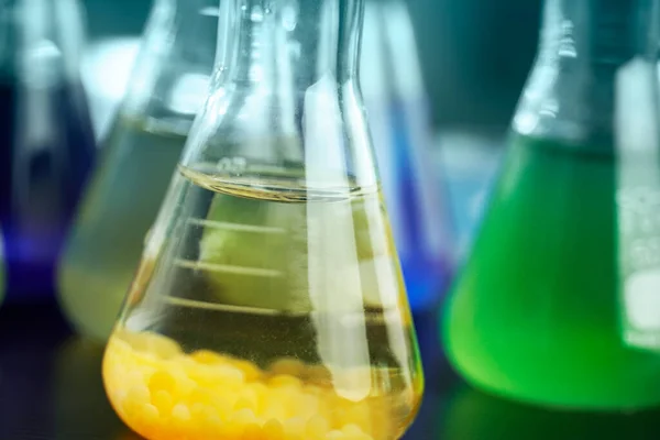 化学研究实验室背景下科学玻璃瓶中的橙色和绿色溶液 — 图库照片