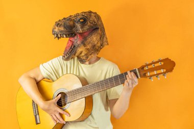 Dinozor maskeli, turuncu arka planda gitar çalan mutlu, tanınmayan bir kadının portresi.
