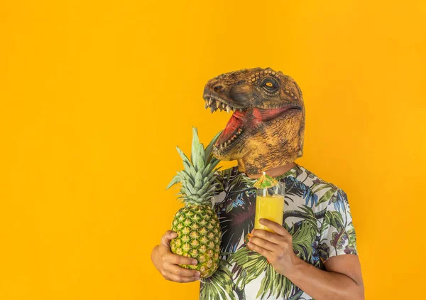Man wearing dinosaur animal head mask holding pineapple fruit and drinking cocktail or juice .Surreal party , person in party concept