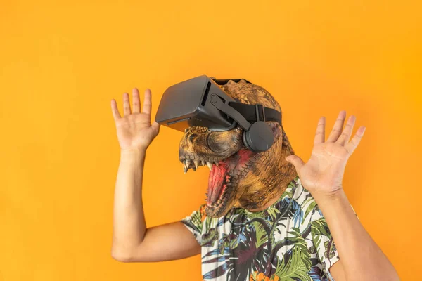 Happy man wearing dinosaur head mask with hands up wearing virtual reality goggles.Unrecognizable and surreal person, Smartphone using VR headset