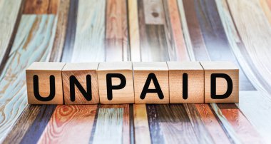 Tahta bir bloğa yazılmamış bir kelime. Tasarımınız ve kavramlarınız için çizgili arkaplan üzerine UnPaID metni.