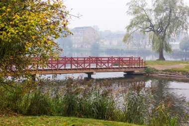Sisli bir sabahta parktaki tahta köprü.