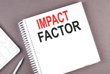 Not defterine hesap makinesi ve kalemle IMPACT FACTOR metni, iş