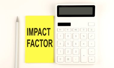 Kalem ve hesap makinesinin yanındaki sarı etikete IMPACT FACTOR yaz