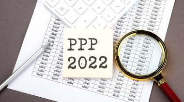 PPP 2022 etiketli metin, hesap makinesi ve büyüteçle