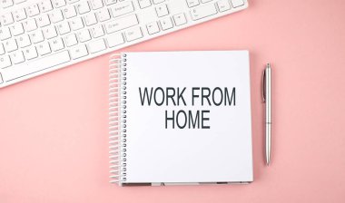 Klavyeli pembe ofis masası ve ev işi yazılı not defteri.