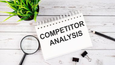 COMPETITOR ANALYSIS metin kavramı tahta arka planda ofis araçları ile deftere yazın