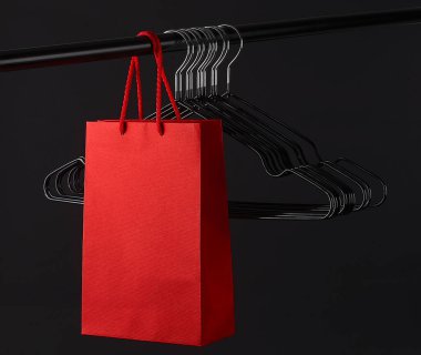 Bir sürü siyah askı ve çubuklu kırmızı çanta. Mağaza konsepti. Kara Cuma. Boşluğu kopyala