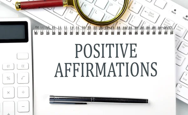 POSITIVE AFFIRMATIONS Text on the notepad with calculator and keyboard