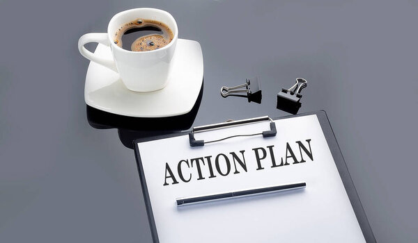 ACTION PLAN text on the paper sheet with coffee on the black background