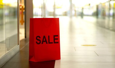 Alışveriş merkezinin arka planında duran kırmızı kağıt alışveriş torbaları.