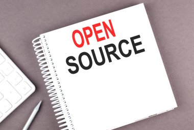 Hesap makinesi ve kalemle deftere açık SOURCE metni, iş
