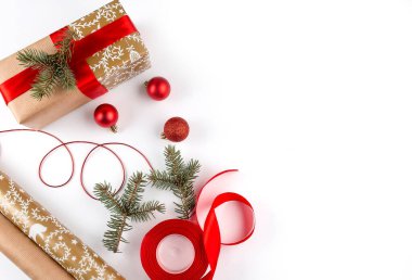 Noel süsleri ve kırmızı kurdele, beyaz arka planda hediye.