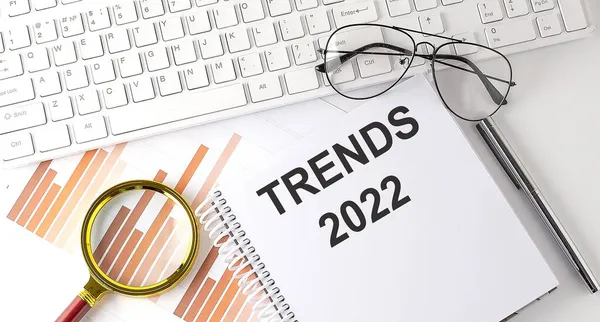 Not defterine klavye, grafik ve gözlük ile yazılmış TRENDS 2022 metin