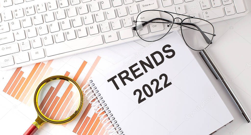 TRENDS 2022 text written on notebook with keyboard, chart,and glasses