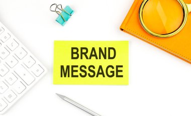 Hesap makinesi ve defterin yanında, beyaz arkaplan üzerinde BRAND MESAGE metni olan etiket