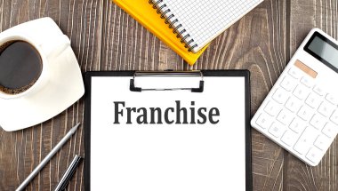 Kahve, hesap makinesi ve defterle kağıda yazılmış FRANCHISE metni. İş dünyası