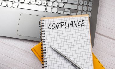 Dizüstü bilgisayardaki deftere yazılmış COMPLIANCE metni