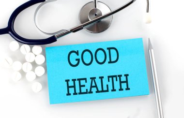 Steteskoplu, haplı, kalemli, tıbbi konseptli bir masaya iyi sağlık mesajı yaz..