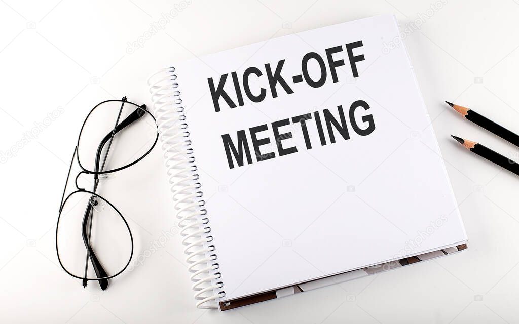 Notepad with text KICK-OFF MEETING . White background. Business