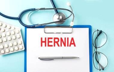Mavi arka planda steteskop ve haplarla ilgili HerNIA metni olan kağıt