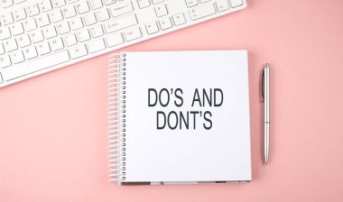 Klavye ve not defterli pembe ofis masası, metin DO 'ları ve DONT' lar