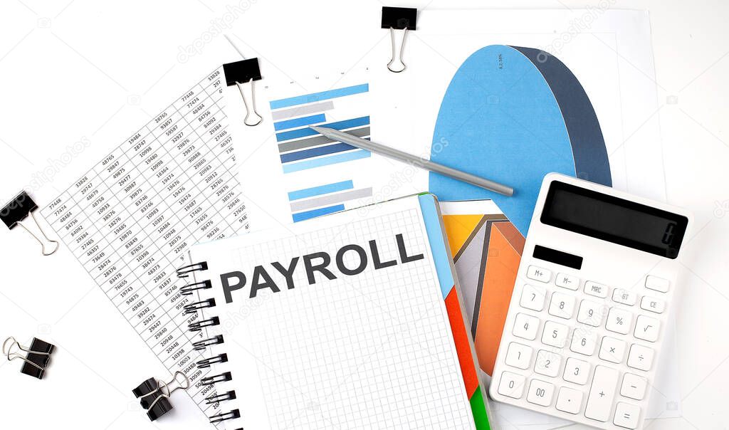 Text PAYROLL on a notebook on diagram and charts with calculator and pen