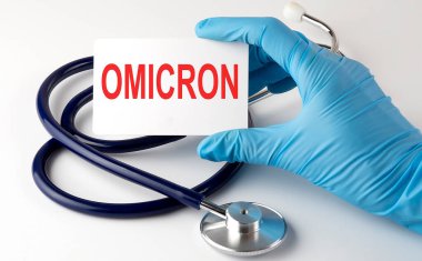 Üzerinde OMICRON malzemeleri, haplar ve stetoskop olan bir kart. Tıbbi