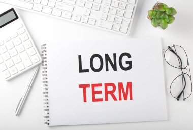 Klavyesi, not defteri ve hesap makinesi olan bir ofis masası. Üst Görünüm, Uzun Dönem metni