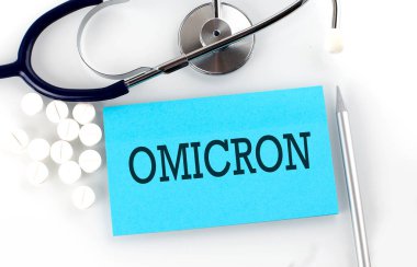 OMICRON 'u steteskoplu, haplı, kalemli, tıbbi konseptli bir masaya yaz..