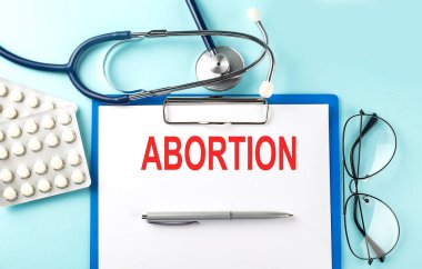 Mavi zemin üzerinde steteskop ve haplarla birlikte metin ayrılması olan kağıt