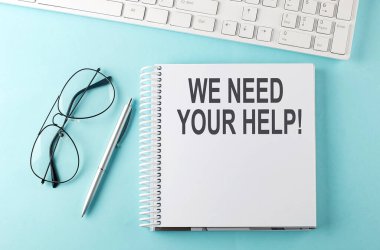 Klavye, not defteri, mavi arka planda kalem ve gözlük. Yardımınıza ihtiyacımız var.