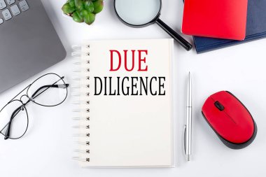 Not defterindeki beyaz arkaplanda dizüstü bilgisayarı olan DUE DILIGENCE metni