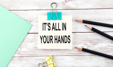 Kalemli çıkartmalar, yazılı defter hepsi senin elinde, tahta arka planda.