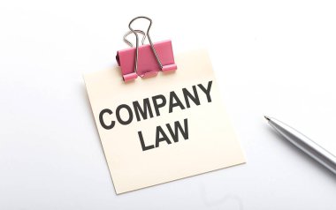 Etiketin üzerinde beyaz arkaplanda kalemle birlikte COMPANY Yasa metni
