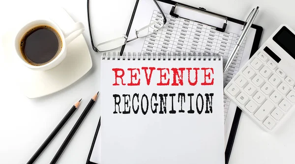 REVENUE RECOGNITION text on paper with calculator, notepad, coffee ,pen with graph