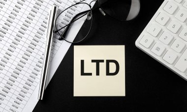 Siyah arkaplanda gözlüklü, grafikli ve hesap makineli çıkartma üzerindeki LTD iletisini kavra