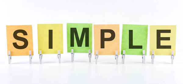 The phrase SIMPLE is written on the multi-colored stickers, on the white background. Business concept, strategy, planning.