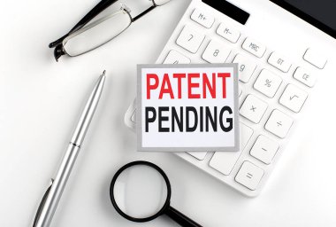 Hesap makinesi, gözlük ve büyüteçle yapıştırılmış PATENT PENDING metni