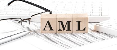 Klavye, hesap makinesi, çizelge, gözlük ile ahşap küp üzerine AML yazıldı.