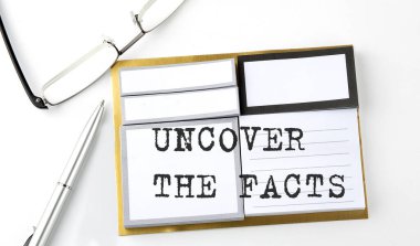 UNCOVER THE FACTS text on sticky notes with glasses and pen, business concept