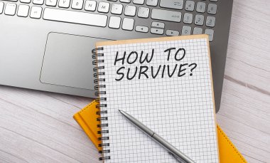 HOW TO SURVIVE text written on notebook on the laptop
