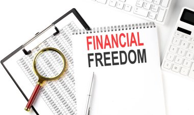 Office desk table with keyboard, notepad ,chart and calculator. Top view , text FINANCIAL FREEDOM