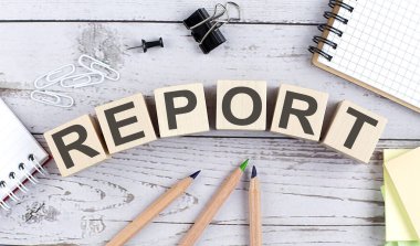 Ahşap blokta, ahşap arka planda ofis araçları olan REPORT metni