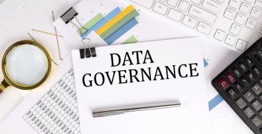 DATA GOVERNANCE text on the white paper on light background with charts paper ,keyboard and calculator