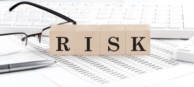 RISK written on wooden cube with keyboard , calculator, chart,glasses.Business