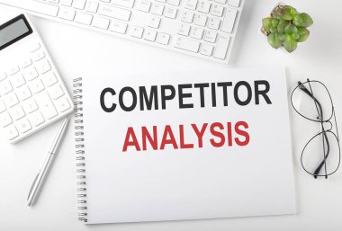 Klavyesi, not defteri ve hesap makinesi olan bir ofis masası. Üst Görünüm, metin COMPETITOR ANALYSIS